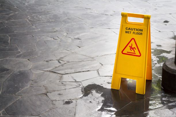 wet floor sign sitting in puddle of water on the floor